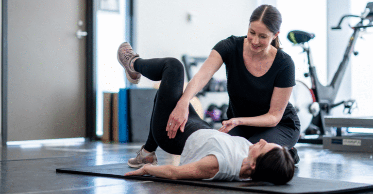 A woman and her personal trainer performing pelvic Exercises on a yoga mat